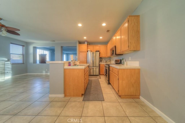 kitchen featuring light brown cabinets, stainless steel appliances, an island with sink, ceiling fan, and light tile patterned floors