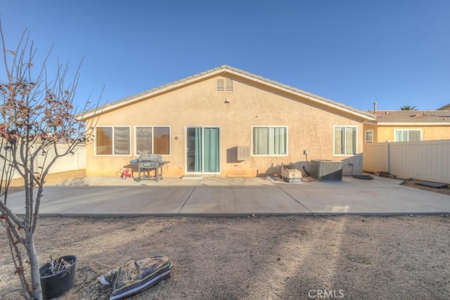 back of property with central AC unit and a patio