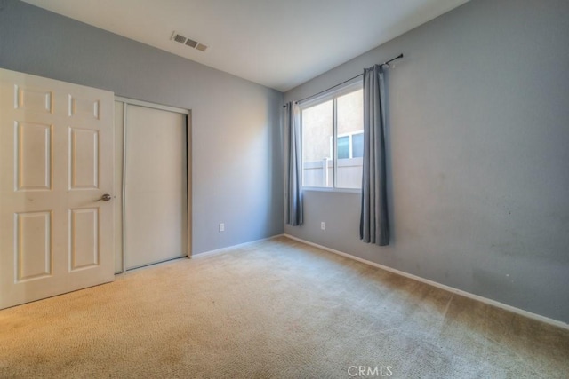 unfurnished bedroom with light carpet and a closet