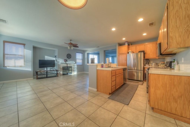 kitchen featuring appliances with stainless steel finishes, a kitchen island, sink, ceiling fan, and light tile patterned floors