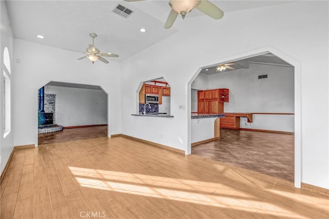 unfurnished living room with lofted ceiling, wood-type flooring, and a wood stove