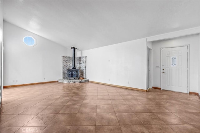 unfurnished living room featuring vaulted ceiling, light tile patterned floors, and a wood stove