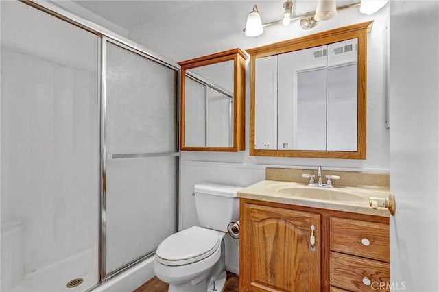 bathroom with a shower with shower door, toilet, and vanity