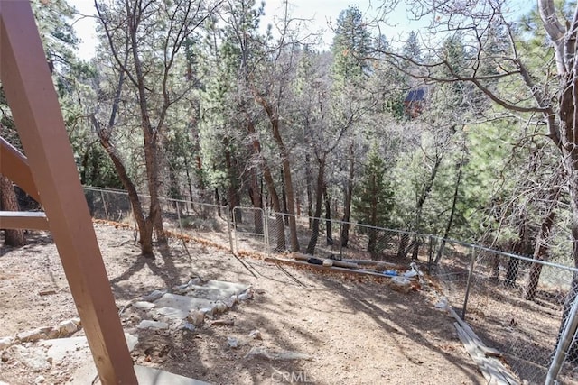 view of yard featuring a fenced backyard and a forest view