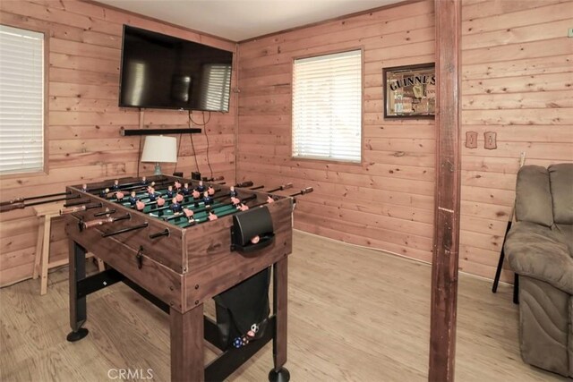 game room with light hardwood / wood-style flooring and wooden walls