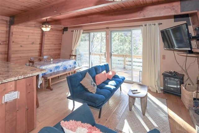 living area with light wood-style floors, wood ceiling, a wood stove, and beam ceiling