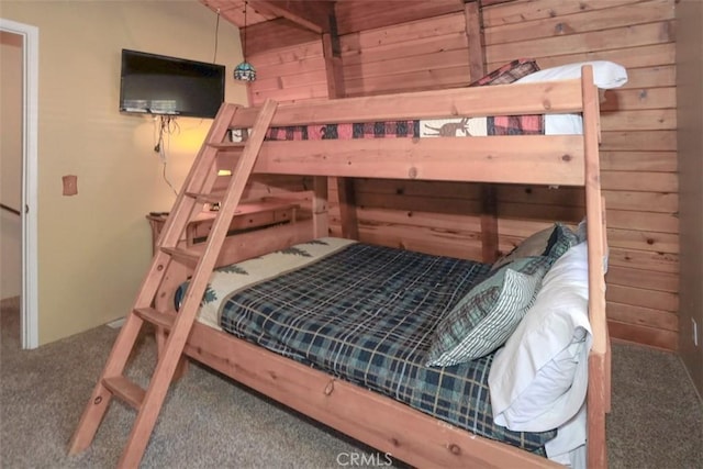 bedroom featuring wooden walls and carpet flooring