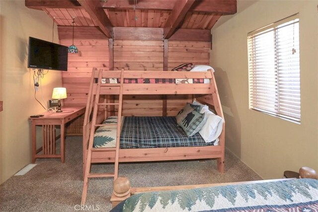 carpeted bedroom with wood ceiling, beamed ceiling, and wooden walls