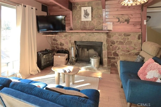 living room with a fireplace, light hardwood / wood-style floors, and wooden walls