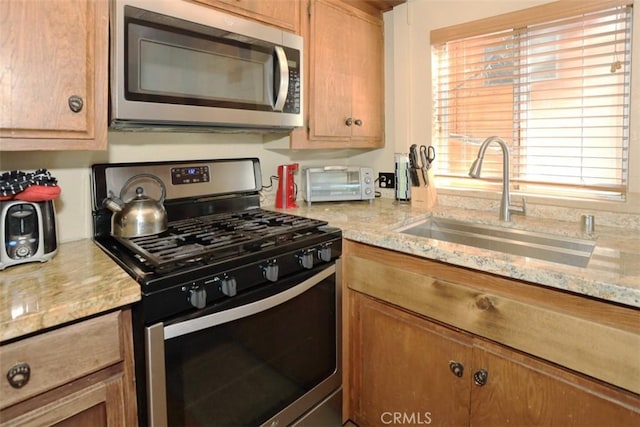 kitchen with light stone countertops, sink, and appliances with stainless steel finishes