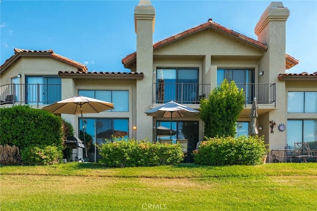 back of property with a balcony and a yard