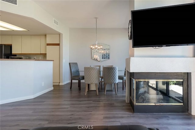 unfurnished dining area with dark hardwood / wood-style flooring, a multi sided fireplace, and a chandelier