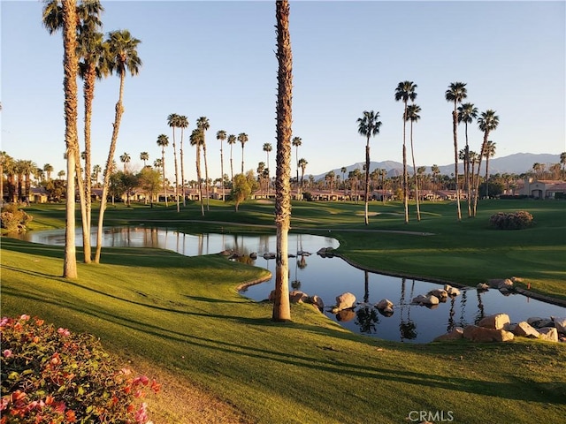 surrounding community with a water and mountain view and a lawn