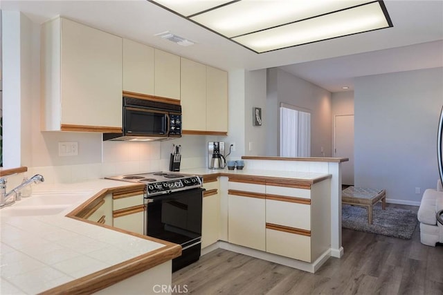 kitchen featuring black appliances, sink, dark hardwood / wood-style floors, kitchen peninsula, and cream cabinets