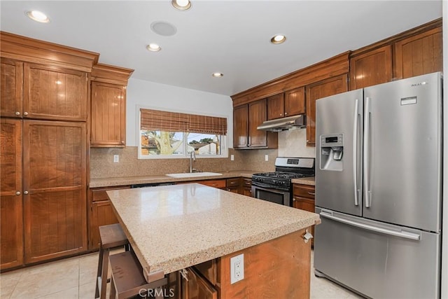 kitchen with a kitchen island, sink, light stone countertops, a kitchen breakfast bar, and stainless steel appliances