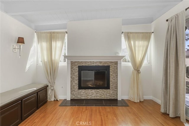 unfurnished living room with beam ceiling and light wood-type flooring