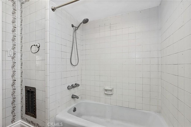 bathroom with tiled shower / bath combo and heating unit