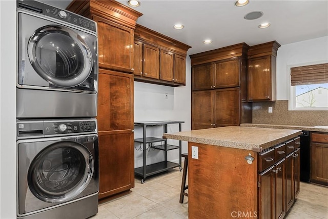 laundry room featuring stacked washer and dryer, cabinets, and light tile patterned floors