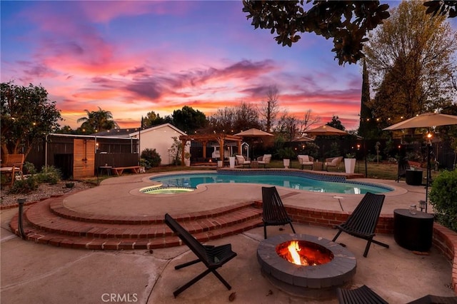 pool at dusk featuring a fire pit and a patio