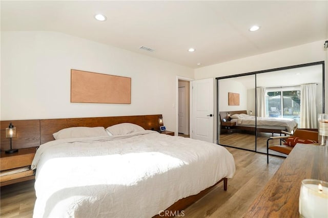 bedroom with lofted ceiling, a closet, and wood-type flooring