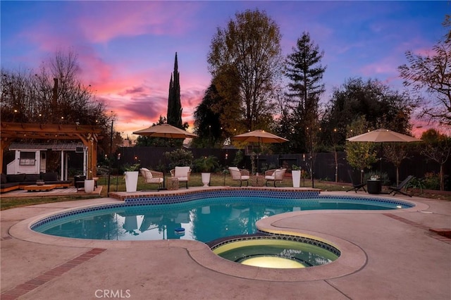 pool at dusk with an in ground hot tub, a patio, and a pergola