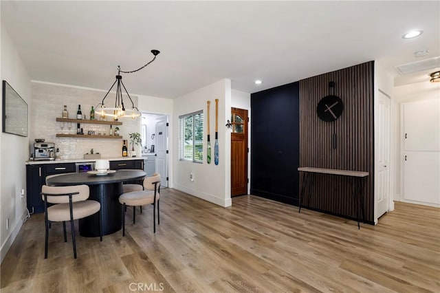 kitchen with light hardwood / wood-style floors, a kitchen breakfast bar, backsplash, and decorative light fixtures