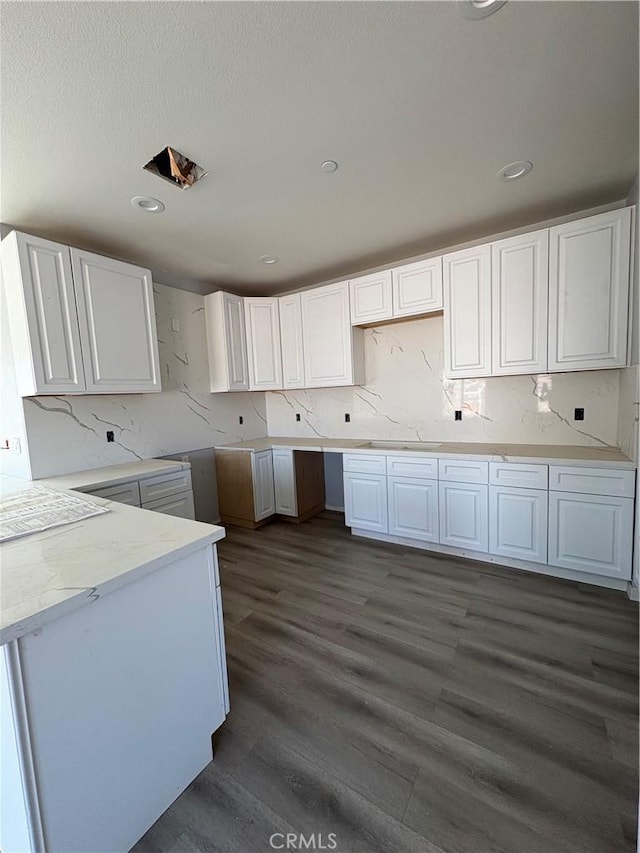 kitchen featuring dark wood-style floors, backsplash, white cabinets, and a sink