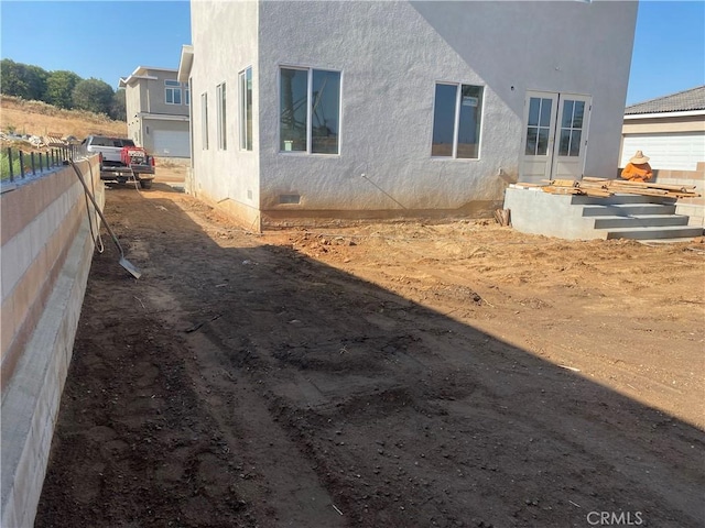 exterior space featuring stucco siding, fence, and crawl space