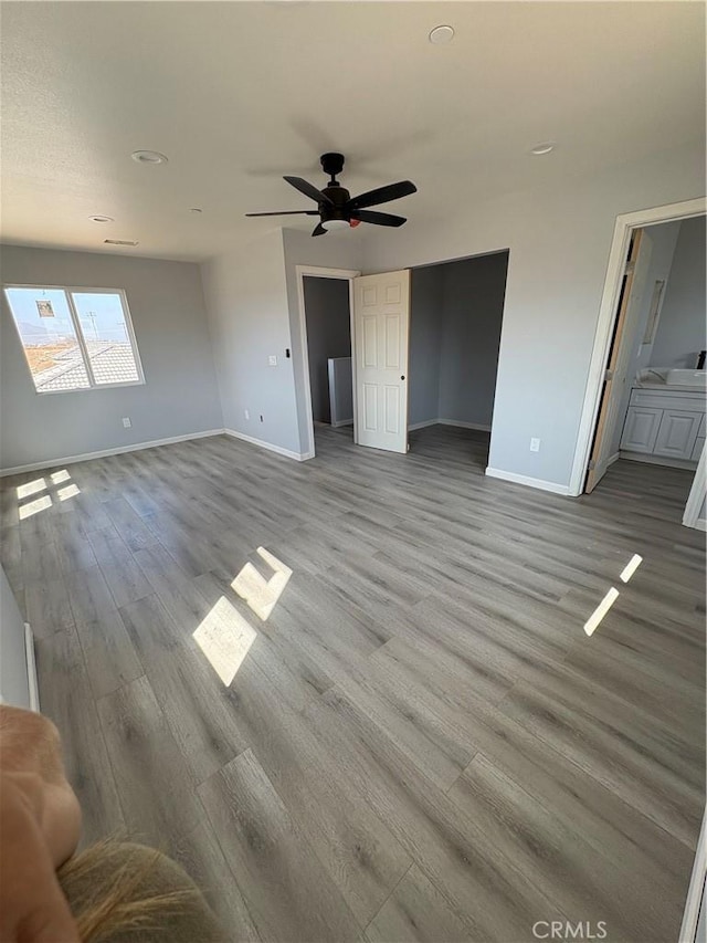 unfurnished living room with ceiling fan, baseboards, and wood finished floors