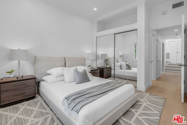 bedroom featuring hardwood / wood-style flooring, crown molding, and a closet