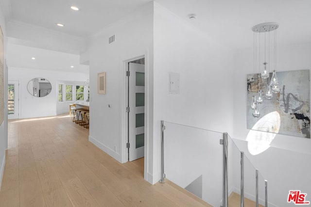 hallway with ornamental molding and light wood-type flooring