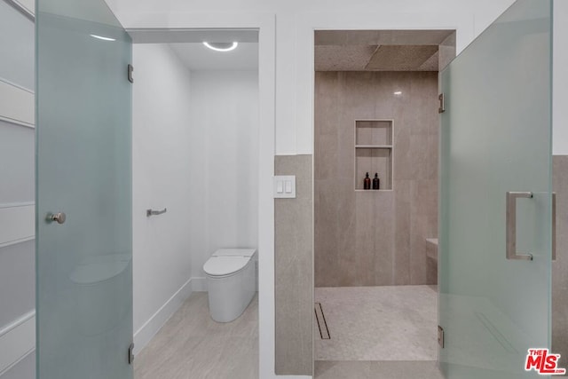 bathroom with a shower with shower door and toilet