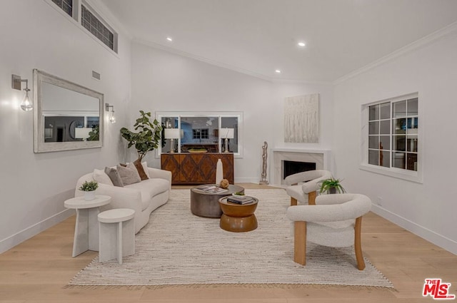 living room with ornamental molding, light wood-type flooring, and a high end fireplace