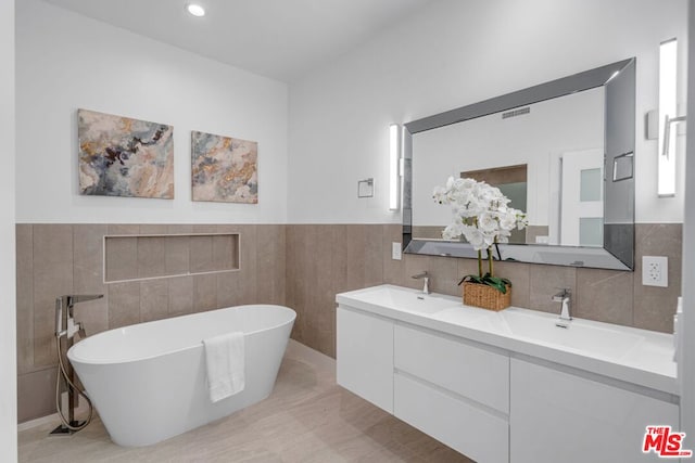 bathroom featuring vanity, a bathtub, and tile walls