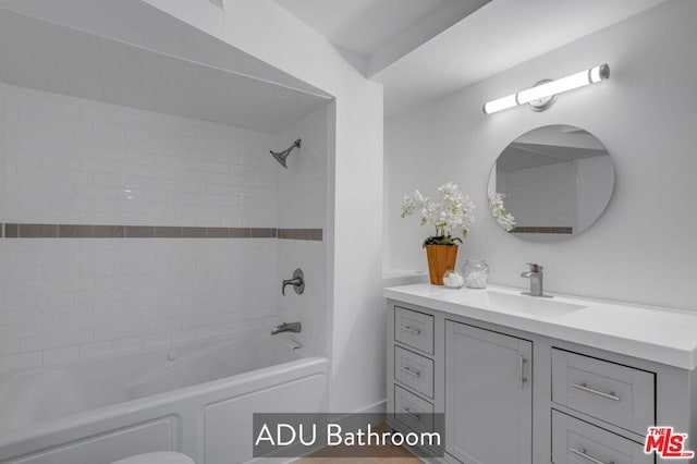 bathroom featuring tiled shower / bath combo and vanity