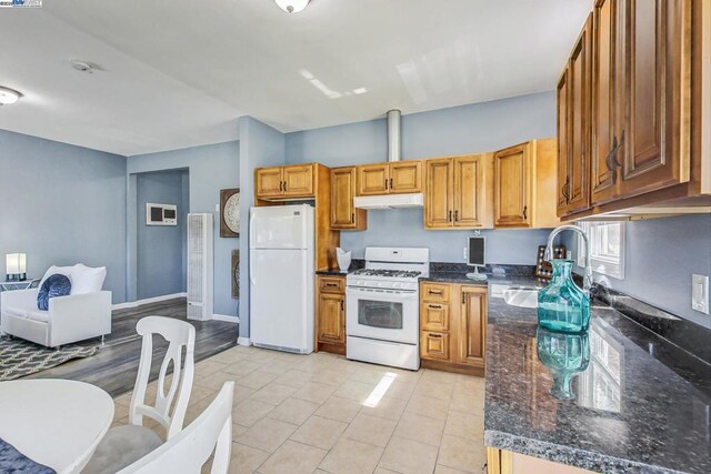 kitchen featuring light tile patterned floors, sink, dark stone countertops, and white appliances