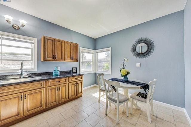 kitchen featuring sink, light tile patterned floors, and dark stone counters