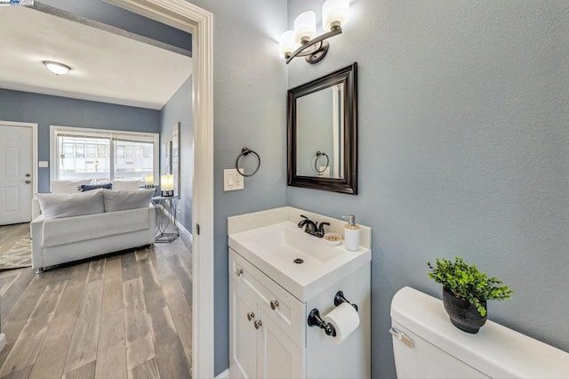 bathroom featuring toilet, vanity, and hardwood / wood-style floors