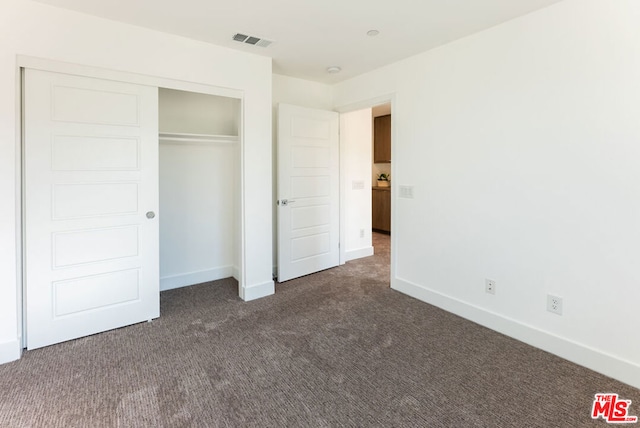 unfurnished bedroom featuring a closet and dark carpet