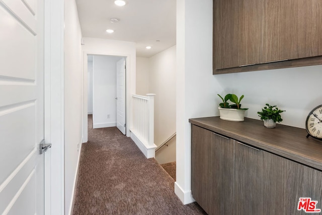 hallway with dark colored carpet