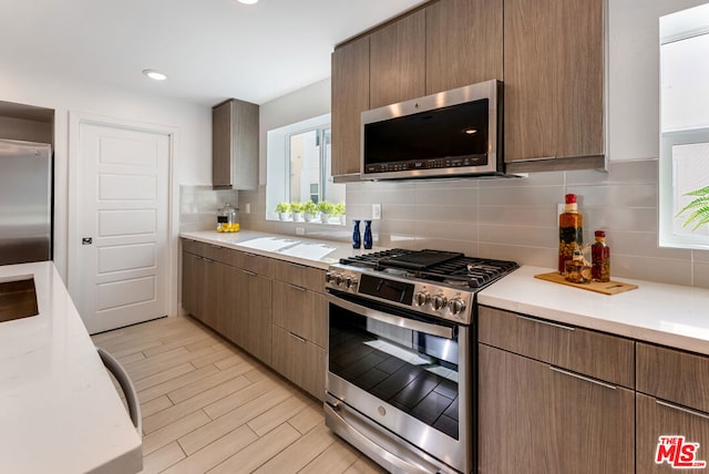 kitchen with light hardwood / wood-style flooring, stainless steel appliances, and tasteful backsplash