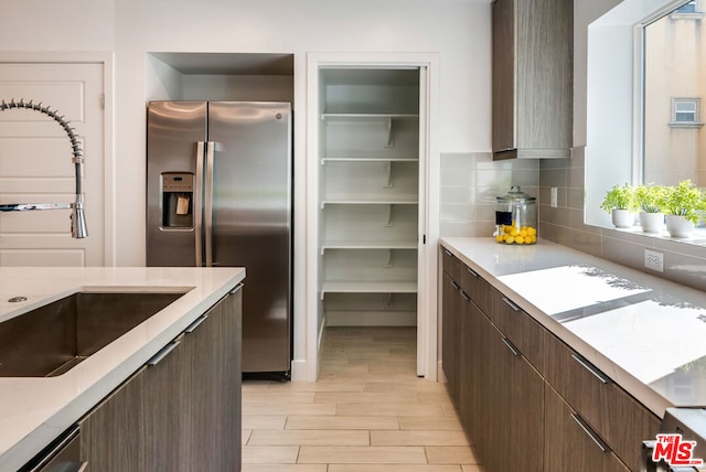 kitchen with appliances with stainless steel finishes, light hardwood / wood-style flooring, dark brown cabinetry, and sink