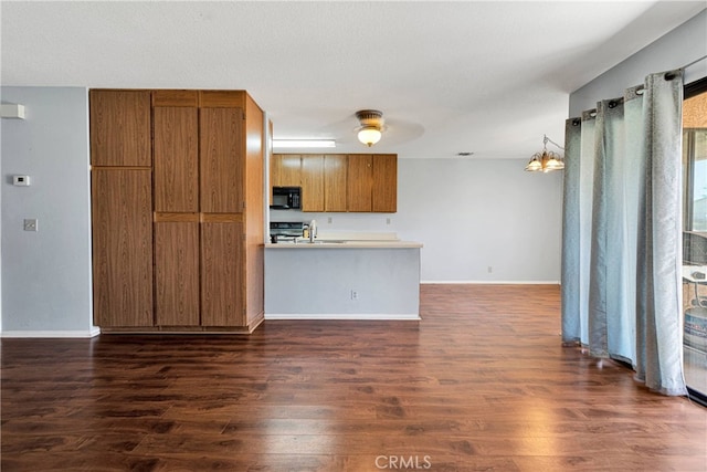 kitchen featuring kitchen peninsula, ceiling fan, stove, dark wood-type flooring, and hanging light fixtures