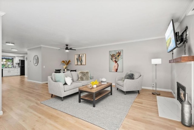 living room with hardwood / wood-style floors, crown molding, a high end fireplace, and ceiling fan