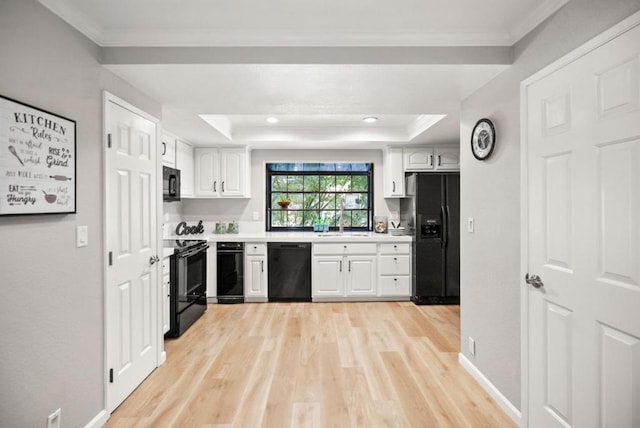 kitchen featuring a tray ceiling, ornamental molding, black appliances, and white cabinets