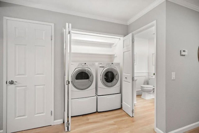 laundry room with light hardwood / wood-style flooring, crown molding, and washer and clothes dryer