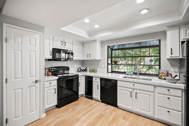 kitchen featuring white cabinetry, sink, black appliances, a raised ceiling, and light wood-type flooring