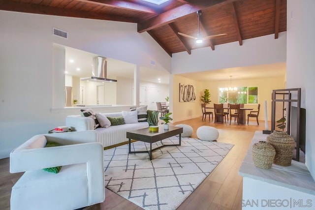 living room with wooden ceiling, wood-type flooring, high vaulted ceiling, ceiling fan with notable chandelier, and beamed ceiling