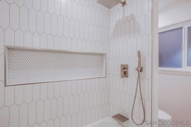 bathroom with toilet and tiled shower / bath