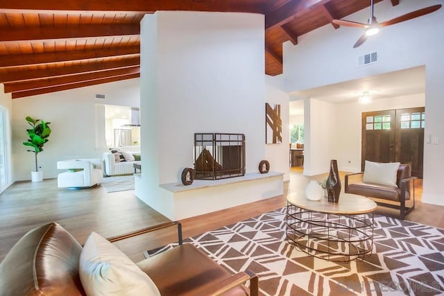 living room featuring ceiling fan, wood-type flooring, wood ceiling, and beamed ceiling